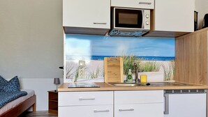 A compact kitchenette with a microwave, a sink, and a wooden cutting board. - Gollwitzer Park (Insel Poel) by Interhome (Gollwitz (Insel Poel))