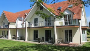A two-story building with a red-tiled roof, multiple balconies, and a patio area with outdoor furniture. - Gollwitzer Park (Insel Poel) by Interhome (Gollwitz (Insel Poel))