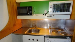 A compact kitchen with a sink, two microwave ovens, and a dishwasher.