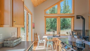 Una cucina moderna con un'isola grande, pensili in legno e ampie finestre che si affacciano sulla foresta.