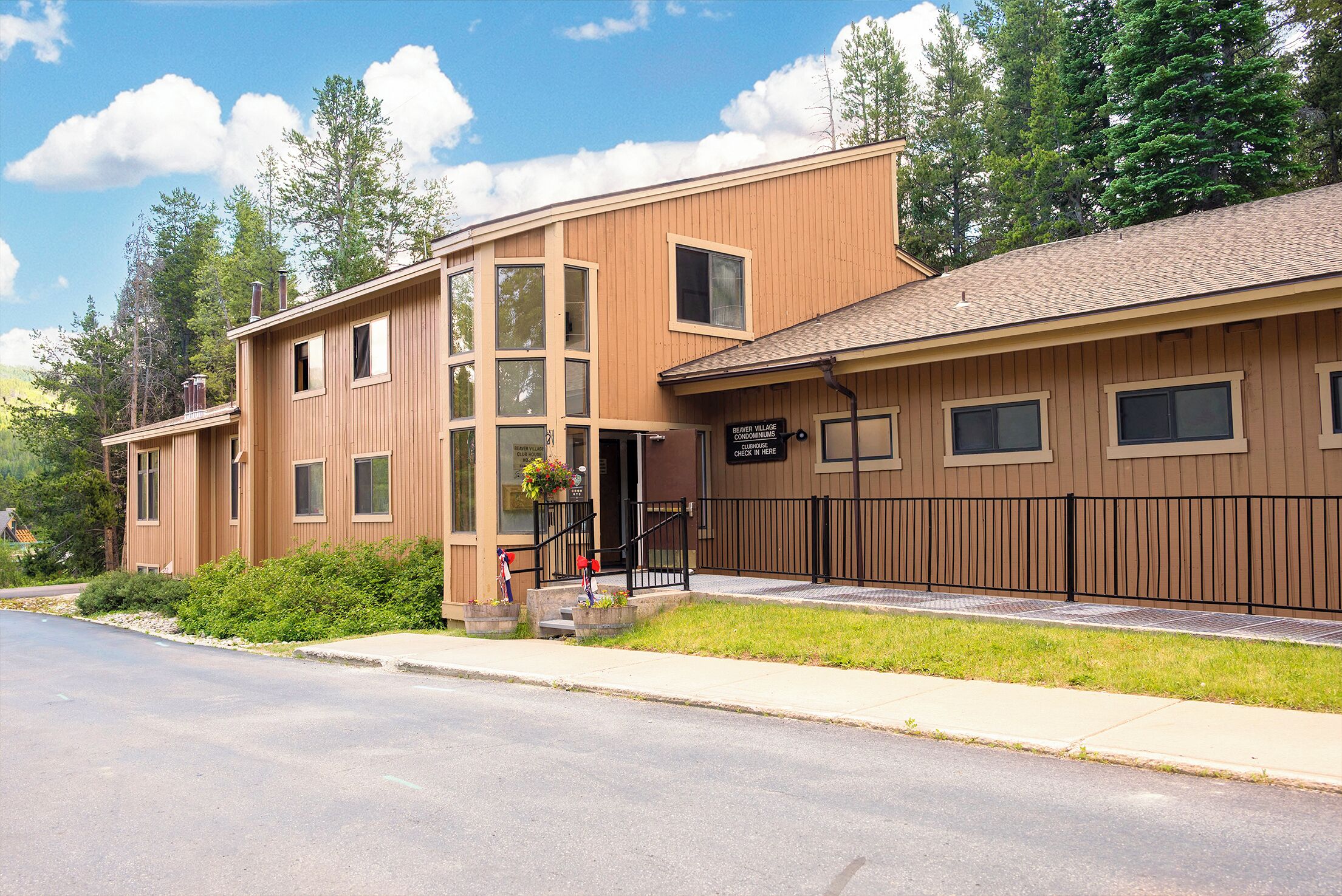 Modern wood-sided property nestled among towering trees on a quiet residential street, offering a peaceful forest retreat setting.