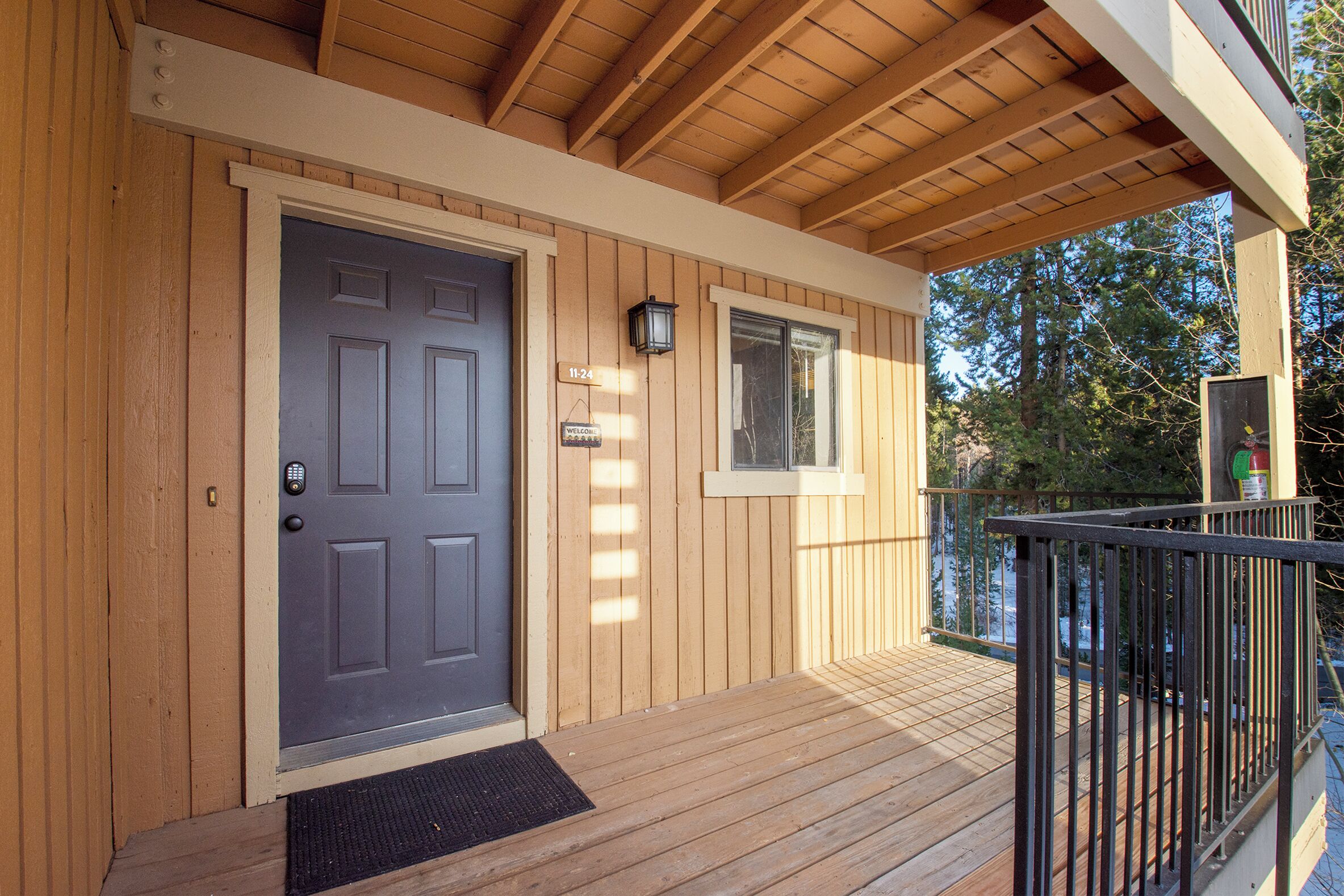 A wooden exterior with a dark grey door, a small window, and a balcony with a black railing.