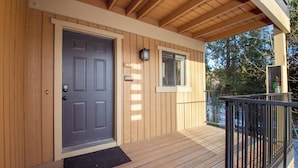 A wooden exterior with a dark grey door, a small window, and a balcony with a black railing. - Beaver Village Unit #1124 4 bedroom Beaver Village modern & extra unit amenities (Winter Park)