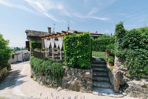 Eine steile Steintreppe führt zu einem traditionellen Haus mit Ziegeldach und einem kleinen Garten.