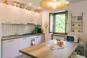 A modern kitchen with white cabinets, a wooden countertop, a sink, a stove, and a window with a view of greenery. - Ancient farmhouse in the countryside (Costermano)