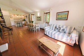 A spacious living area with a sofa, a wooden bench, a dining table with chairs, a kitchen in the background, and a staircase leading to an upper floor. - Ancient farmhouse in the countryside (Costermano)