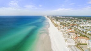 A coastal town with a long sandy beach, residential buildings, and a clear view of the ocean. - Spacious Destin home for families! Walk or free shuttle to beach, resort pool! (Destin)