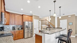A modern kitchen with wooden cabinets, stainless steel appliances, and a granite countertop. - Spacious Destin home for families! Walk or free shuttle to beach, resort pool! (Destin)