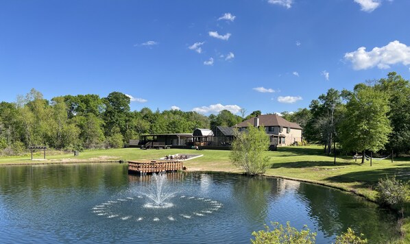 A lakeside property with a dock, a gazebo, and a large house with a covered patio area.