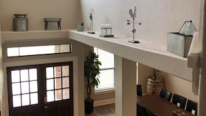 Een ruime keuken met een hoge plafond, een eethoek met een houten tafel en stoelen, en een groot raam dat natuurlijk licht binnenlaat.