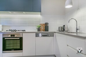 Una cucina moderna con mobili bianchi, una lavastoviglie Bosch, un forno Bosch, un piano cottura a gas e un tostapane in acciaio inossidabile.