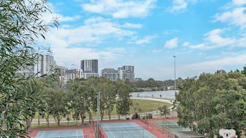 Zona de canchas de tenis exteriores con varias canchas, rodeada de árboles y vistas al lago.