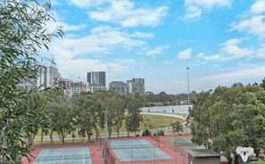 Area di campi da tennis all'aperto, con più campi circondati da alberi e vista sul lago.