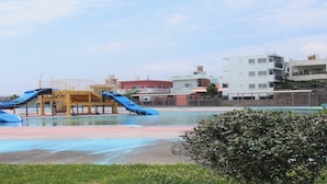 A playground with slides and a pool area, surrounded by buildings. - Lagoon Palace (Kadena)