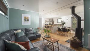 Moderni olohuone, jossa on nahkasohva, sohvapöytä ja ruokailutila. Taustalla näkyy keittiö.