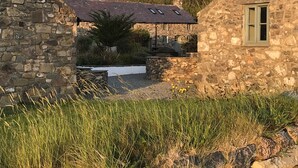 A stone building with a sloped roof and a small window. - The Hay Barn - Exclusive 2 bedroom stone cottage (Llyn Peninsula)