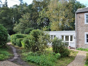 A stone building with a garden path leading to a white door. - 2 bedroom accommodation in Waverton, near Wigton (Waverton, near Wigton)