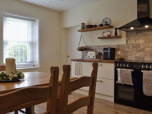 A kitchen with wooden cabinets, a stove, a toaster, and a window with blinds. - 2 bedroom accommodation in Waverton, near Wigton (Waverton, near Wigton)