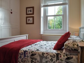 Une chambre à coucher avec un lit, une fenêtre et deux tableaux encadrés accrochés au mur.