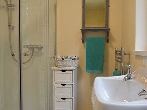 Un baño con ducha de vidrio, un lavamanos blanco y un espejo sobre él.
