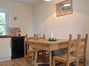 A dining area with a wooden table and chairs, a white candle centerpiece, and a painting on the wall. - 2 bedroom accommodation in Waverton, near Wigton (Waverton, near Wigton)