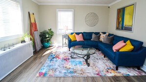 A living room with a blue sectional sofa, a glass coffee table, and a colorful rug. - Excellent Location, Family & Pet Friendly, Walk to Main St, Close to everything (Bethlehem)
