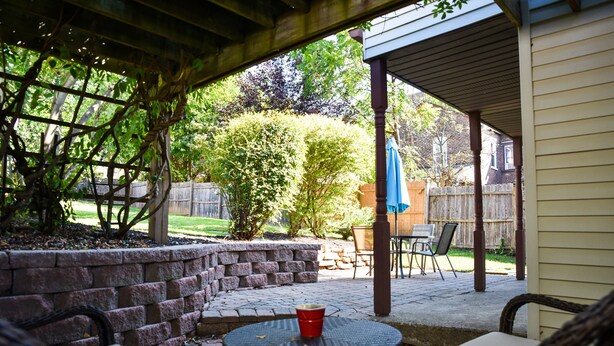 An outdoor patio with a round table and wicker chairs, a brick wall, and a wooden fence in the background. - Excellent Location, Family & Pet Friendly, Walk to Main St, Close to everything (Bethlehem)