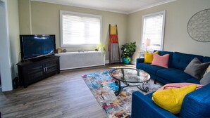 A living room with a television, blue sofa, colorful rug, and a radiator. - Excellent Location, Family & Pet Friendly, Walk to Main St, Close to everything (Bethlehem)