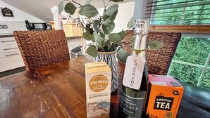 A kitchen with wicker chairs, a bottle of Italian sparkling brut, a box of Cornish tea, and a handwritten note. - 2 bedroom accommodation in Fowey (Fowey)