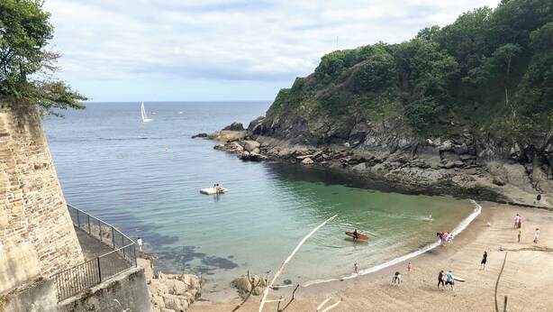 A coastal beach with a stone wall, clear water, and a rocky cliff. - 2 bedroom accommodation in Fowey (Fowey)