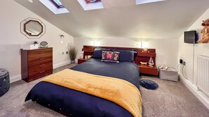 A bedroom with a large bed, skylights, a dresser, a mirror, and a bedside table with a lamp. - 2 bedroom accommodation in Fowey (Fowey)