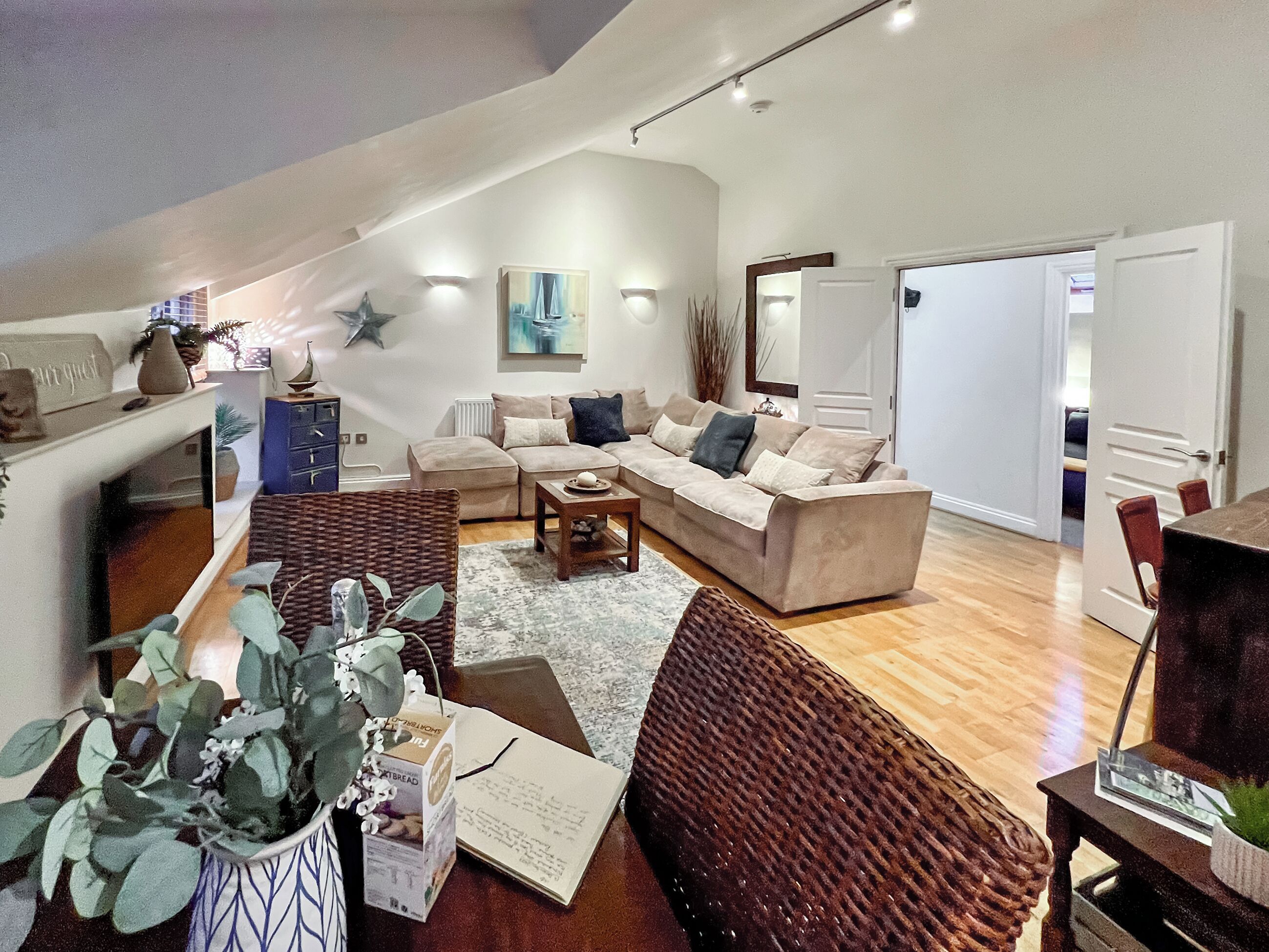 A spacious living room with a high ceiling, a beige sofa, a coffee table, and a large window.