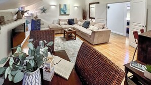 A spacious living room with a high ceiling, a beige sofa, a coffee table, and a large window. - 2 bedroom accommodation in Fowey (Fowey)