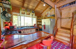 A kitchen with wooden beams, a large island, and a refrigerator. - 24 HOUR SALE 169.00-AUG-12-14th+ AC+TreeHouse Vibe+BBQ+WD+Ocean Cliffs-Cent Loc. (Keaau)