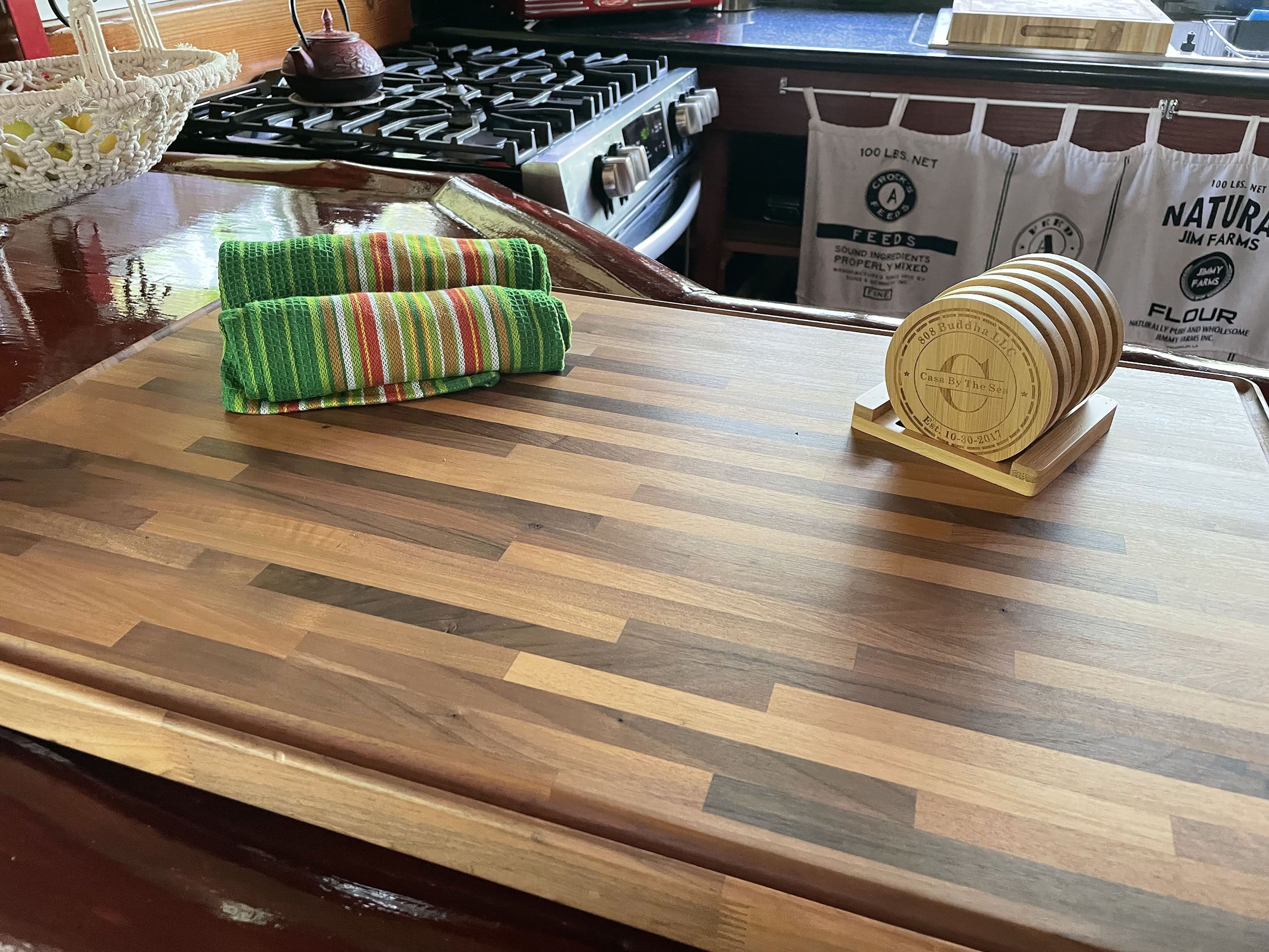 A kitchen counter with a woven placemat, a wooden coaster, and a bag of flour.
