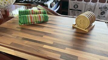 A kitchen counter with a woven placemat, a wooden coaster, and a bag of flour.