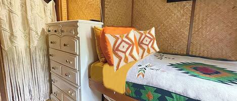 Un dormitorio con una cama, un aparador y una televisión en la pared.
