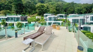Zona de lounge en la azotea con sillones modernos y balaustrada de vidrio con vistas a un paisaje verde exuberante.