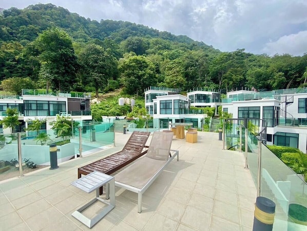 A rooftop lounge area with modern lounge chairs and a glass balustrade overlooking a lush green landscape. - Private 360-degree luxury villa with sea views (Phuket)