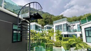 Un edificio moderno con una escalera de caracol, barandillas de vidrio y un jardín bien cuidado.