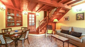Una sala de estar acogedora con una escalera de madera, una mesa de comedor con sillas, un sofá y una lámpara.