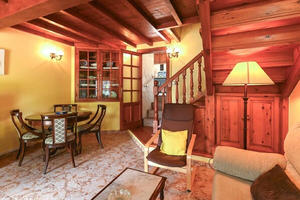 A cozy room with a wooden staircase, a dining area with a table and chairs, and a sofa. - Casa Paula - Near the beach and Hiking (Picones)