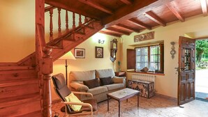 Un salón acogedor con una escalera de madera, un sofá, una mesa de centro y un mueble decorativo.