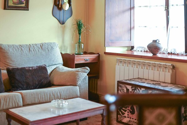 A cozy living room with a sofa, a small table, and a window with a view.