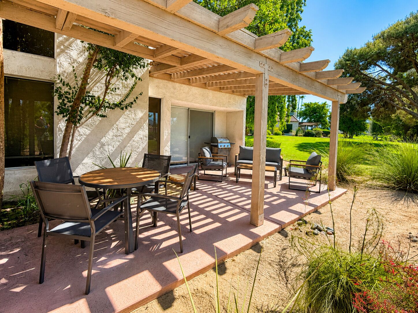 Une terrasse extérieure dotée d’une pergola, d’un barbecue et de sièges.
