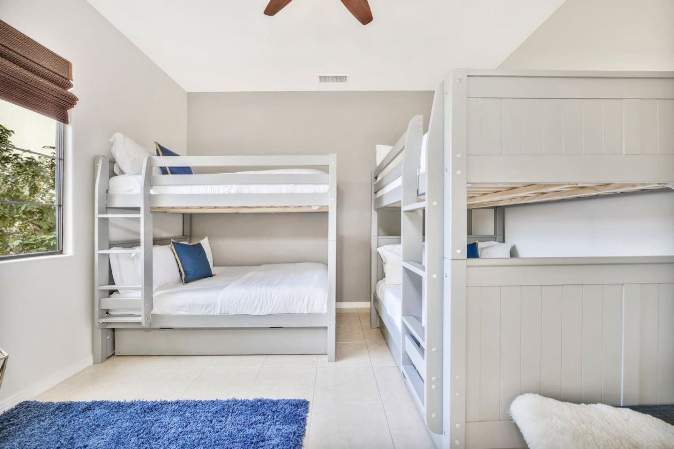 Une chambre avec des lits superposés, un tapis bleu et un tapis blanc et moelleux.