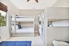 A room with bunk beds, a blue rug, and a white fluffy rug. - Bliss: Pool, Spa, Pool Table, Ping Pong, Fire Pit! (Indio)
