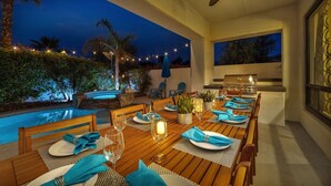An outdoor dining area with a pool, a grill, and a ceiling fan. - Bliss: Pool, Spa, Pool Table, Ping Pong, Fire Pit! (Indio)