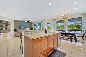 A modern kitchen with a granite countertop, wooden cabinets, and a large island. - Bliss: Pool, Spa, Pool Table, Ping Pong, Fire Pit! (Indio)