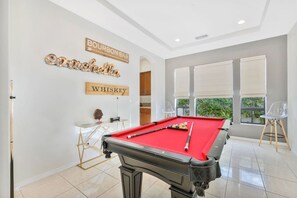 Una mesa de billar en una habitación con un letrero en la pared que dice 'BOURBON BAR' y 'WHISKEY'.